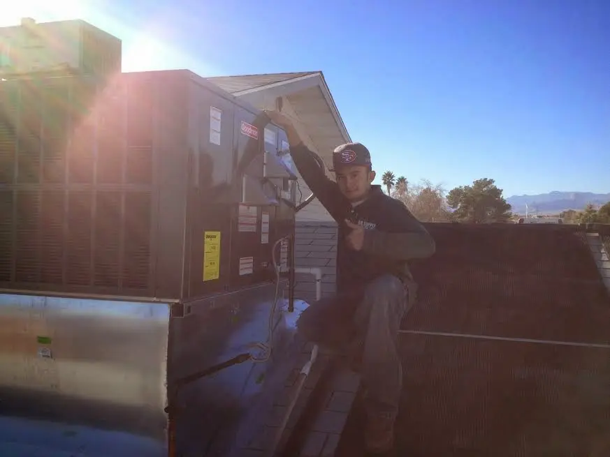 HVAC technician performing AC Tune-Up on a rooftop unit in Burlington